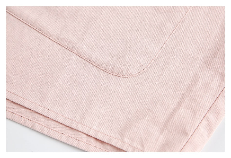 Close-up of the pale pink shirt's patch pocket edge and lower hem stitching.