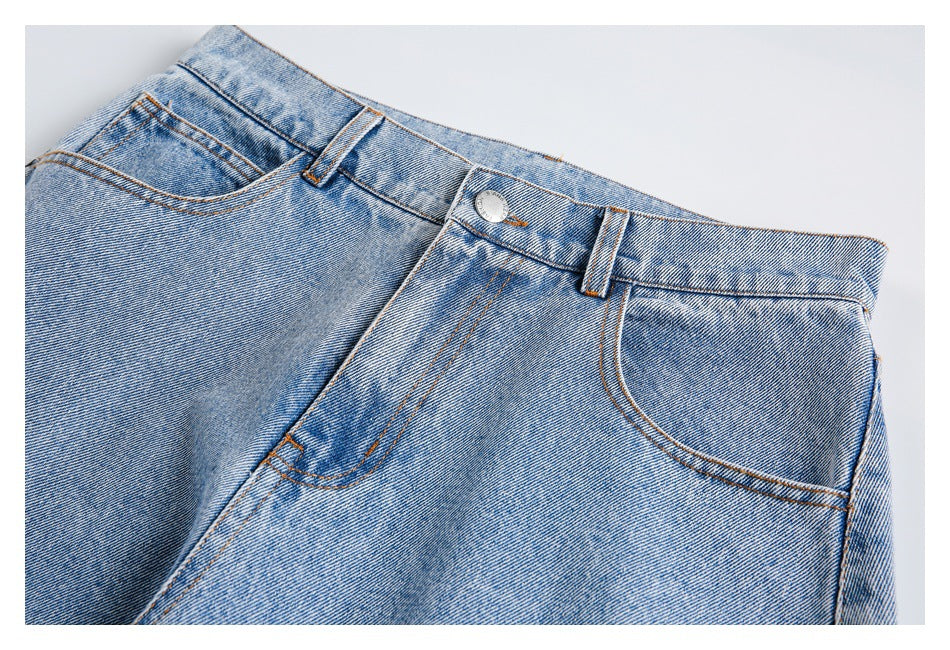 Close-up of the light-wash jeans’ front waistband, button, belt loops and curved pocket stitching.