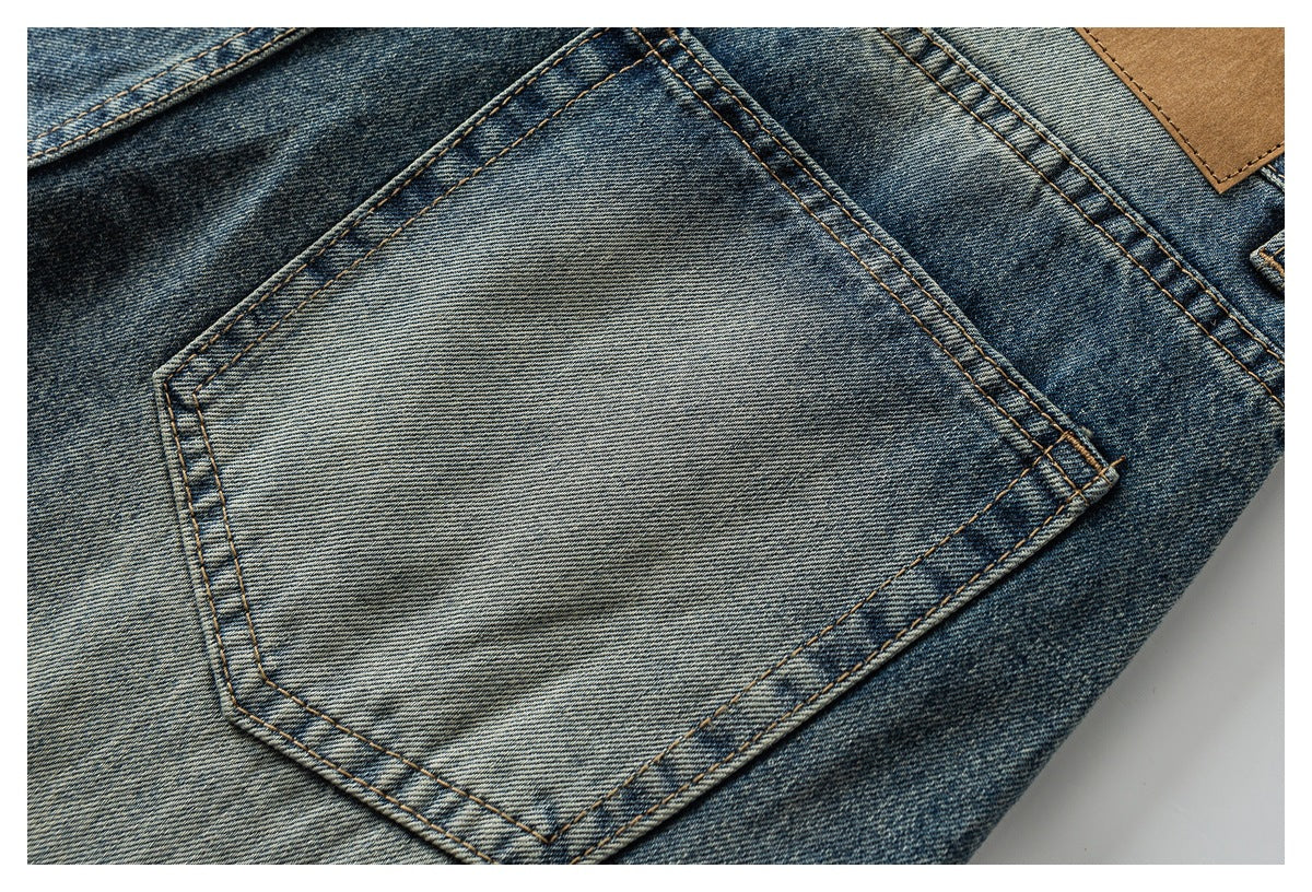 Close-up of a faded blue denim back pocket with contrasting double stitching and a tan waistband patch.