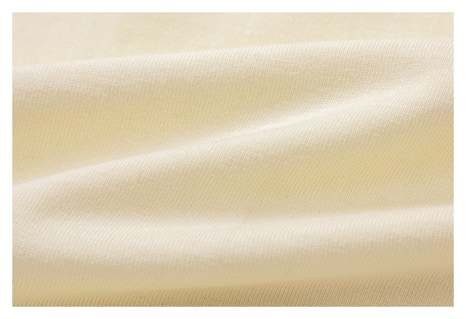 Macro view of the ivory fabric's fine knit texture and soft folds.
