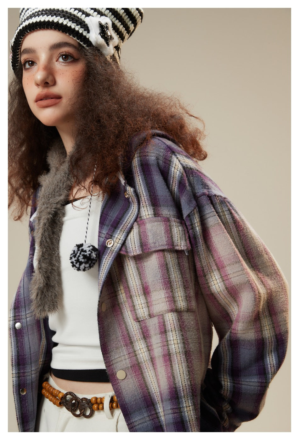 Close view of a model wearing a purple plaid jacket with flap pockets and metal snaps over a white top.