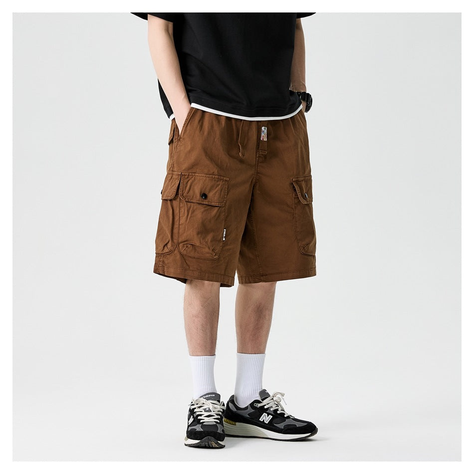 Model wearing light brown knee-length cargo shorts with a black tee and sneakers, front view