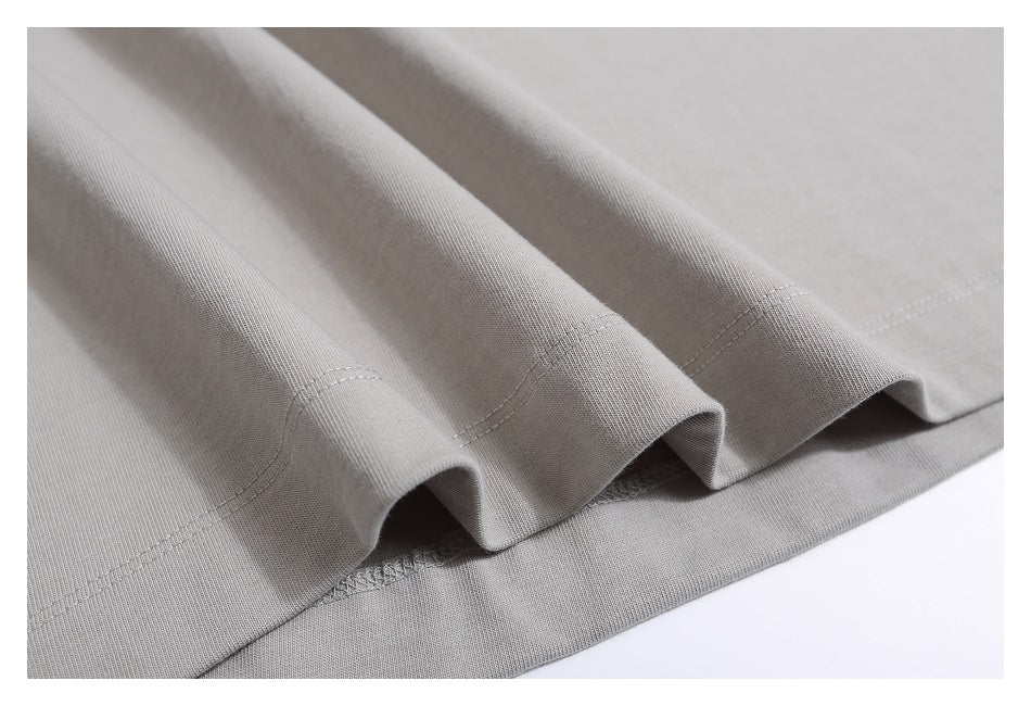 Close-up of the light gray shirt's stitched hem and softly draped fabric.