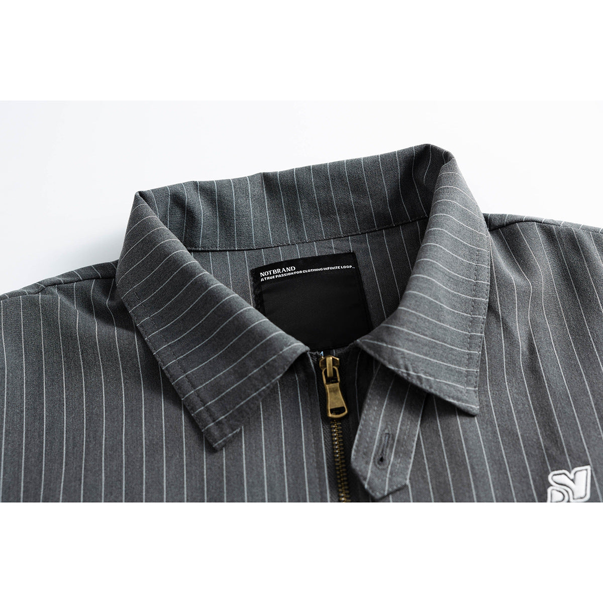 Close-up of a charcoal pinstripe shirt collar, brass zipper and inner neck label.