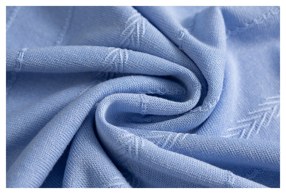 Close-up of light blue knit fabric draped in folds, showing the knit texture and stitched pattern.