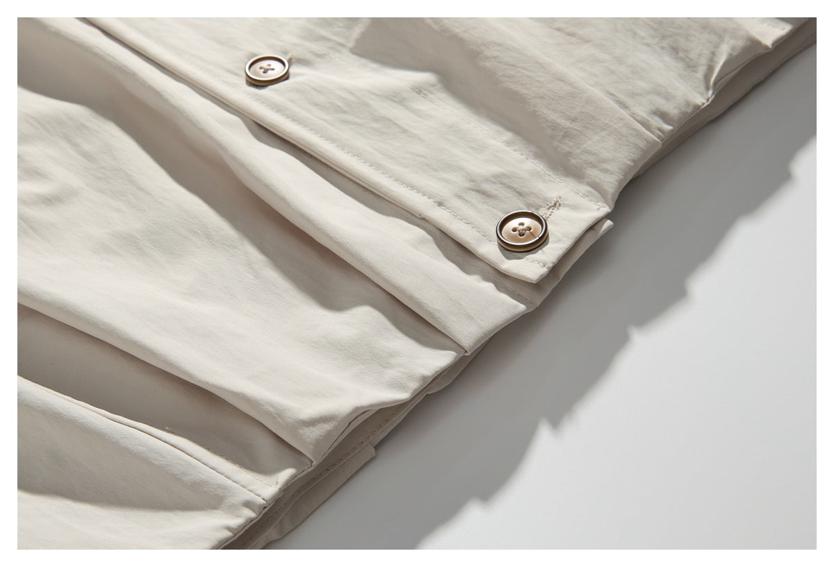 Close-up of the off-white garment's buttoned hem with two brown buttons and visible stitching.