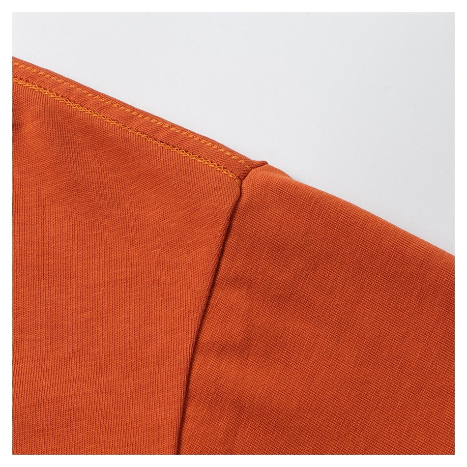 Close-up of an orange garment shoulder seam with contrasting yellow stitching.