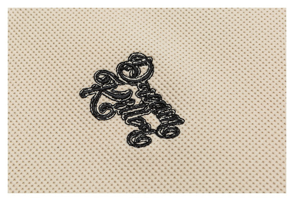 Close-up of black embroidered script on beige textured knit fabric.