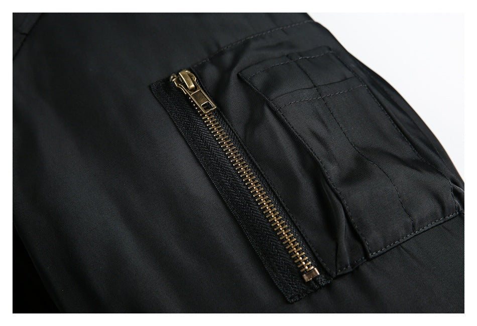 Close-up of a black jacket sleeve utility pocket with a brass-tone zipper.