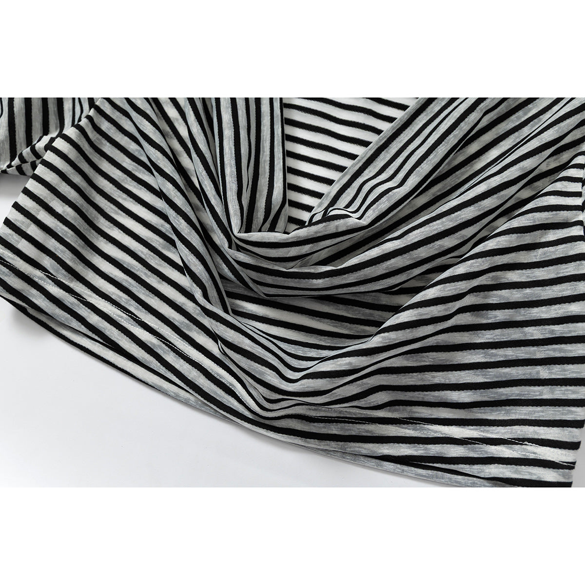 Close-up of black and gray striped fabric gathered into soft folds on a white background.