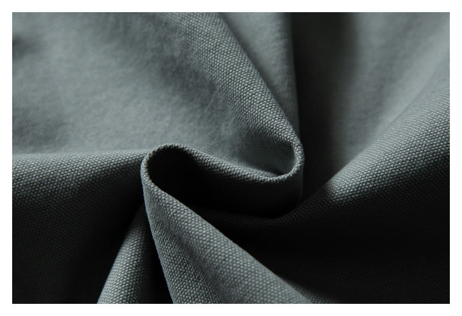 Close-up of gray-green garment fabric folded to show its textured surface and drape.