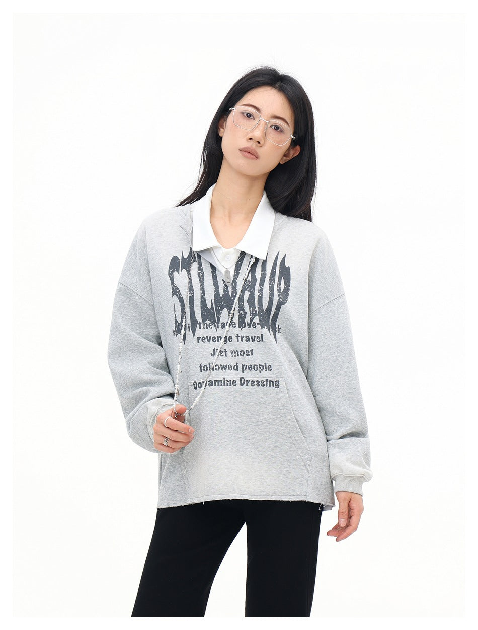 Model wearing a light gray oversized graphic sweatshirt with a white collar and black pants, shown from the front.