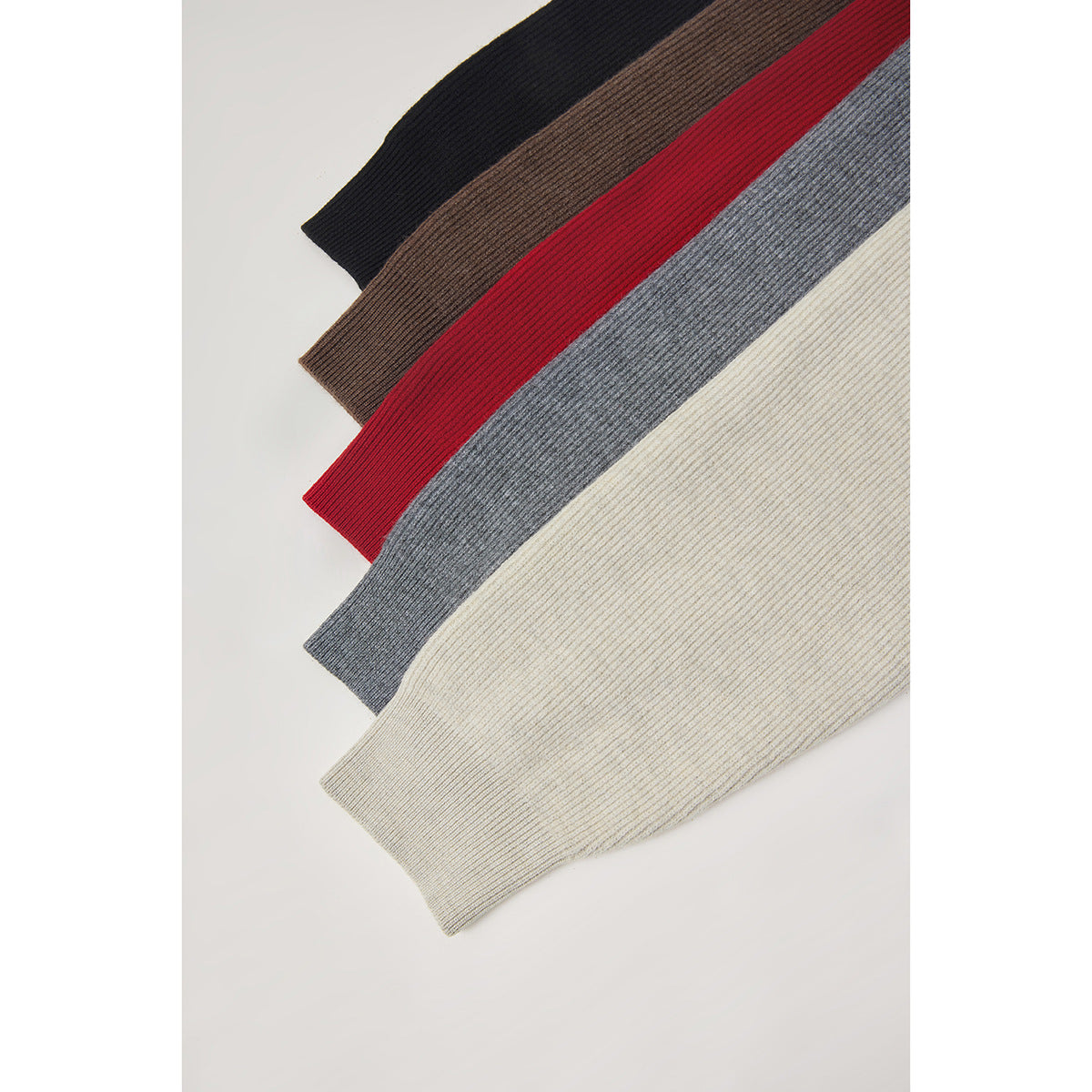 Close-up of ribbed sweater bodies in black, brown, red, gray, and cream arranged diagonally.