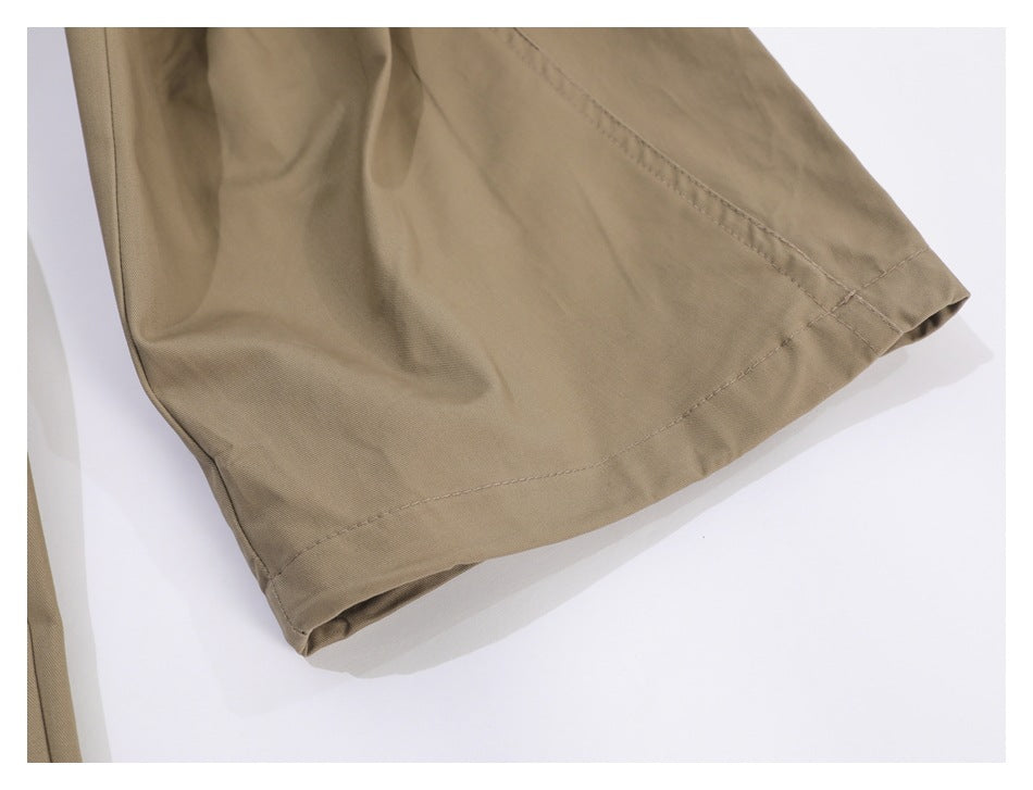 Close-up of the stitched hem on taupe trousers.