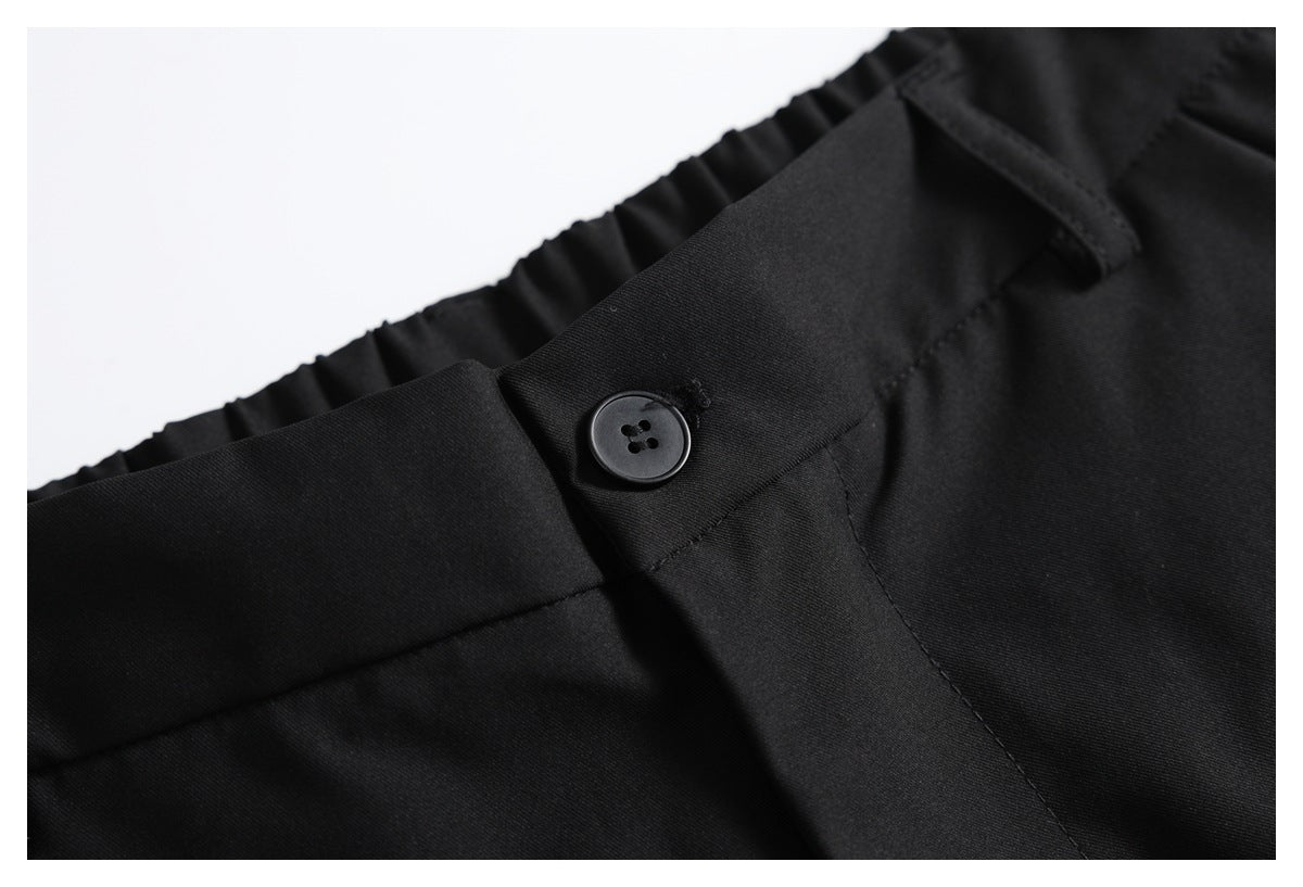 Close-up of black trousers showing a buttoned front closure and gathered waistband.