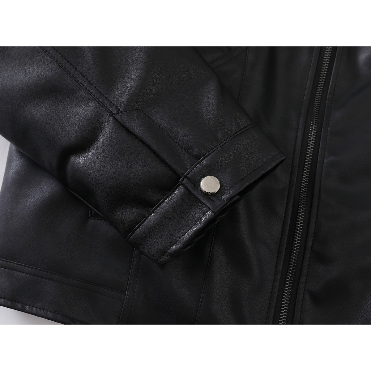 Close-up of a black jacket sleeve cuff with a silver snap beside the front zipper.