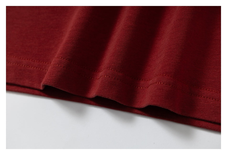 Close-up of the double-stitched bottom hem on a burgundy T-shirt.