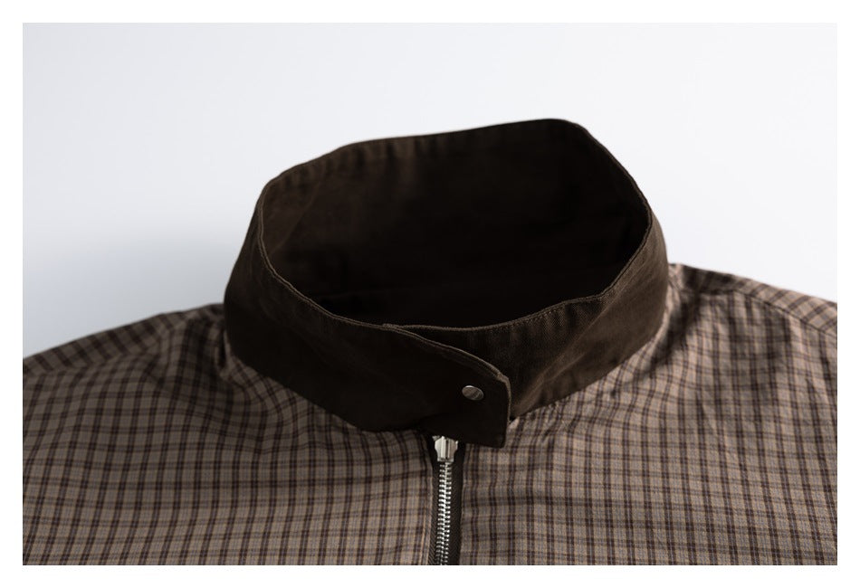 Close-up of the jacket's dark brown stand collar, snap tab, and front zipper over plaid fabric.
