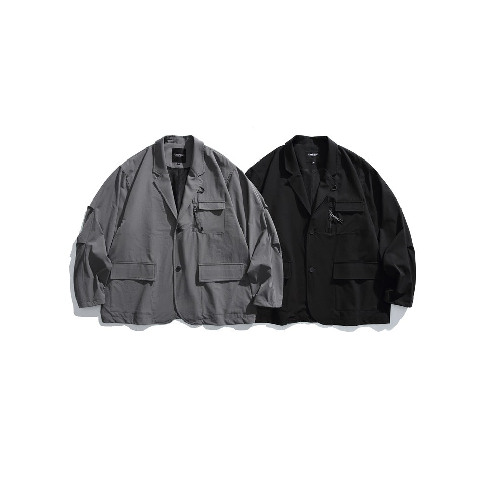 Two front-view blazers displayed together in gray and black, each with a chest pocket and lower flap pockets.