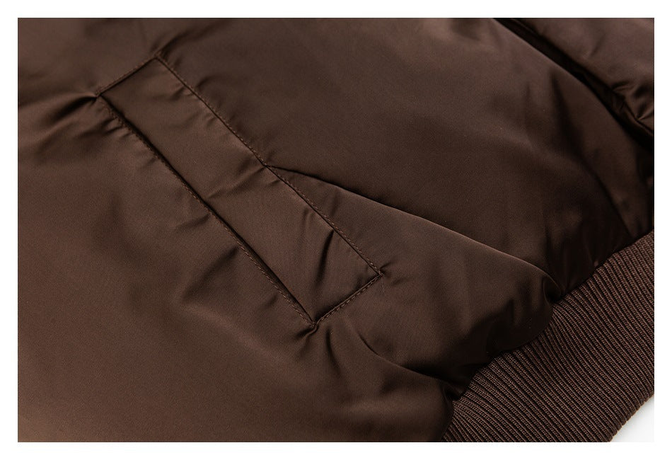 Close-up of a dark brown jacket's angled welt pocket and ribbed hem.