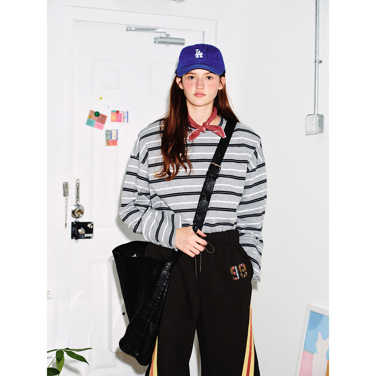Model wearing a gray long-sleeve shirt with black and white horizontal stripes, black shorts with red and yellow side