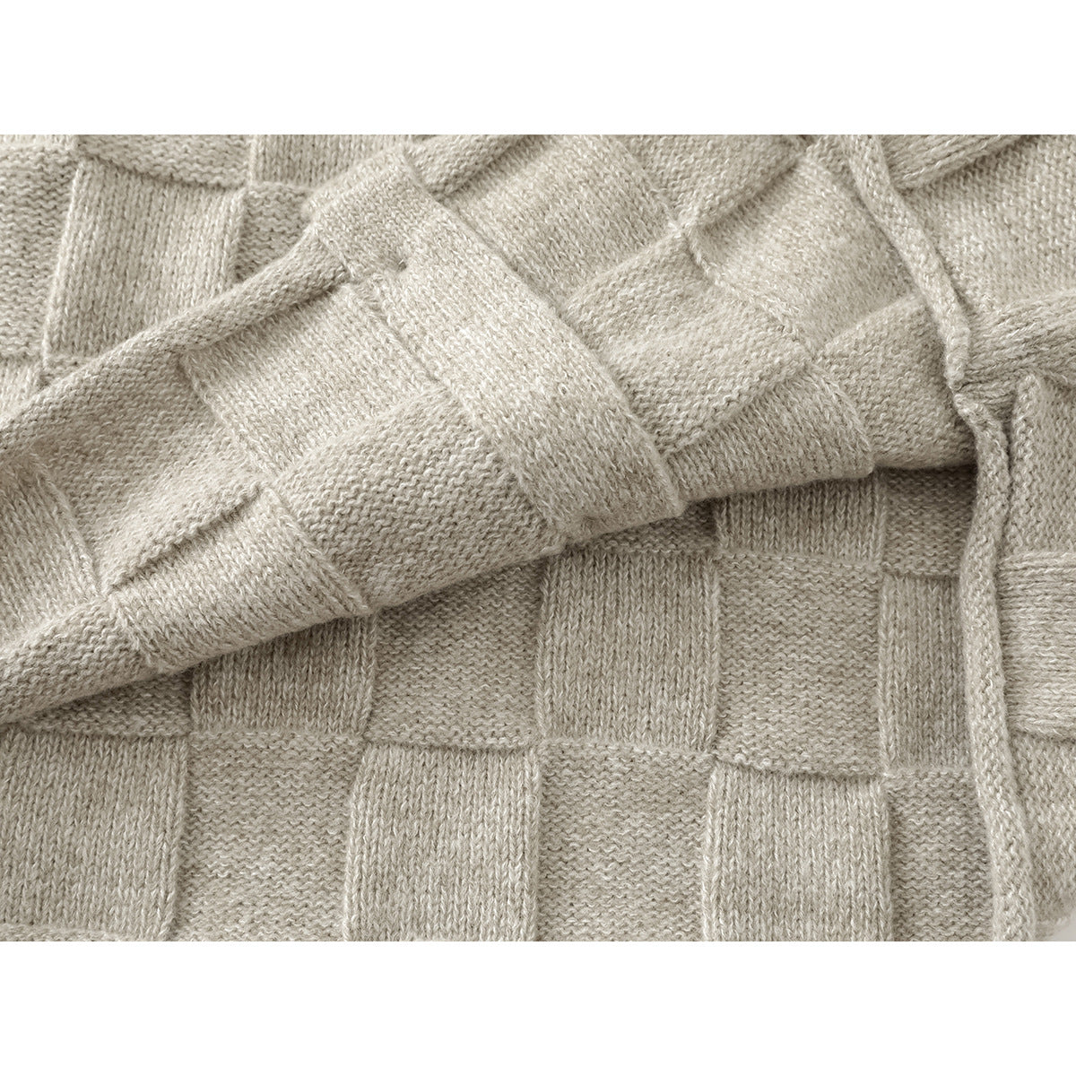 Close-up of the light beige cardigan's textured knit with one sleeve folded across the body.