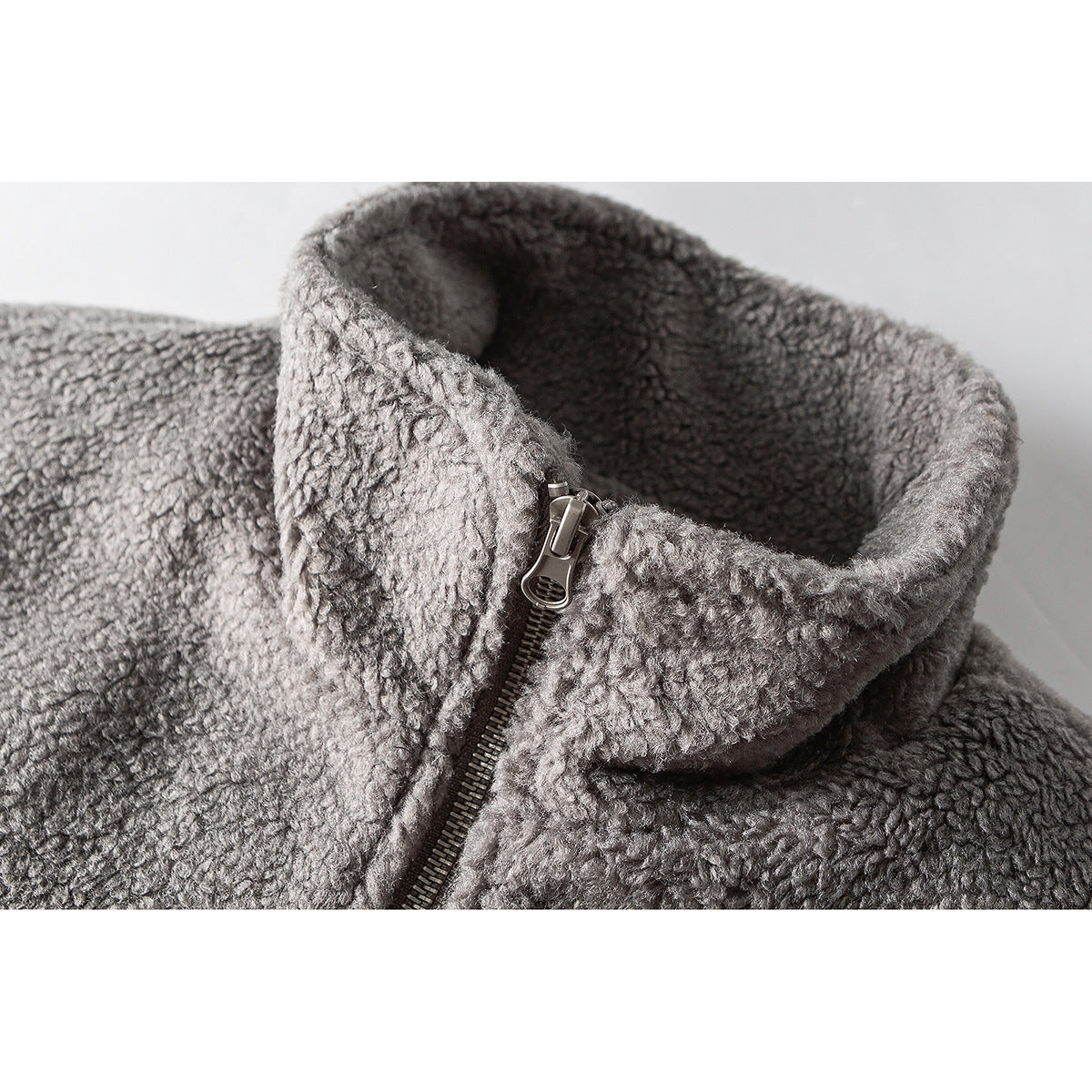 Close-up of a gray textured jacket's tall collar and partially zipped front.