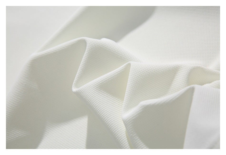 Macro view of white textured garment fabric folded into soft ridges.