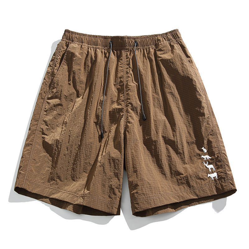 Brown crinkled drawstring shorts with elastic waist and white animal embroidery near the hem, flat lay