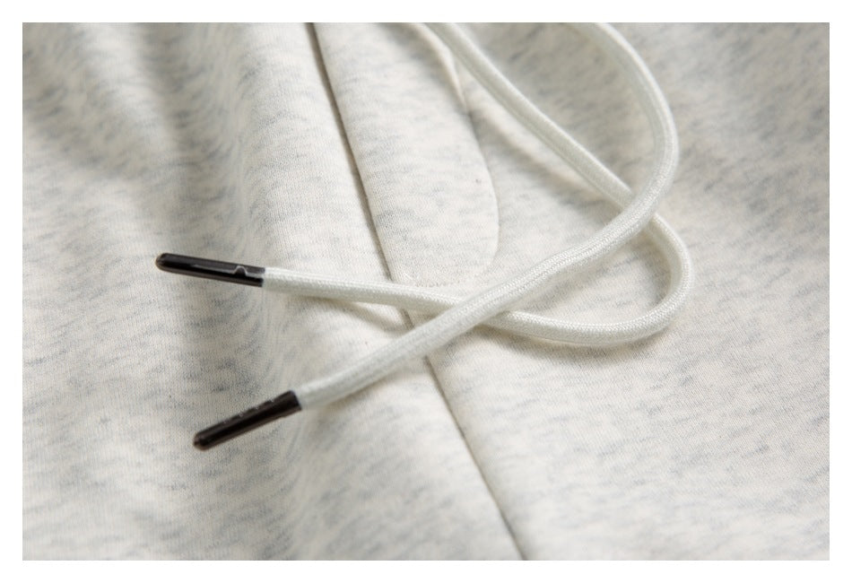 Close-up of light gray marled joggers with a white drawstring and dark aglets.