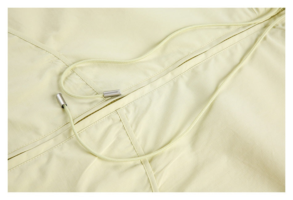 Close-up of pale yellow garment drawcords with metal tips beside a stitched zipper opening.