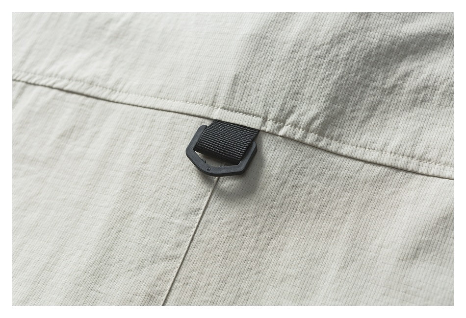 Black webbing loop and plastic ring attached at a seam on light beige ribbed fabric.