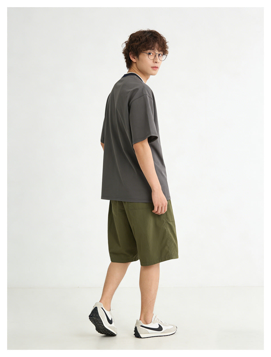 Model shown from the side and back wearing a dark charcoal T-shirt and olive shorts.