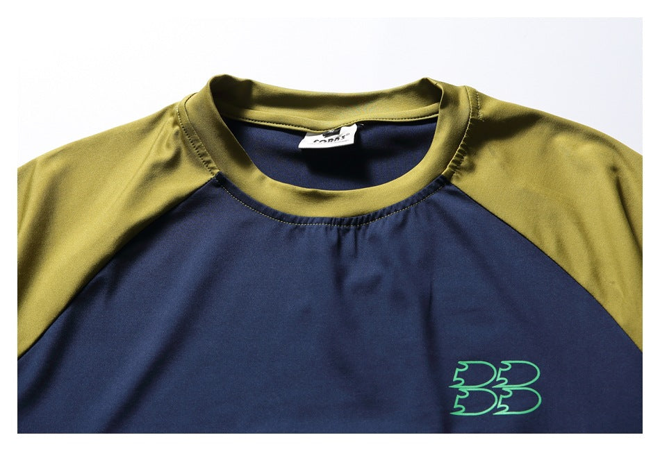 Close-up of a navy T-shirt's olive crew neckline, raglan seams, and small green chest emblem.