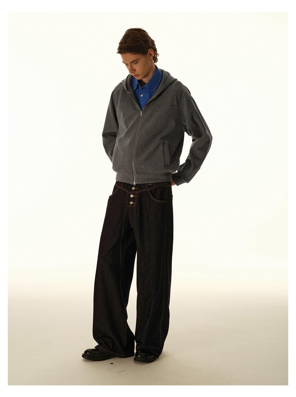 Model wearing a charcoal zip-up hoodie over a blue shirt with wide-leg dark jeans.