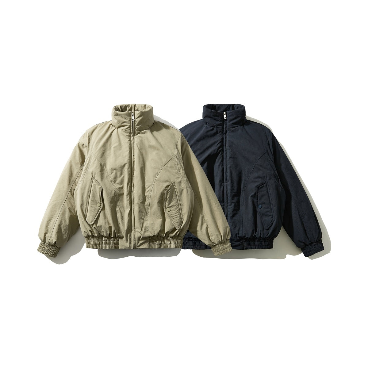 Front view of two stand-collar jackets with front zippers and flap pockets, in olive beige and dark navy.