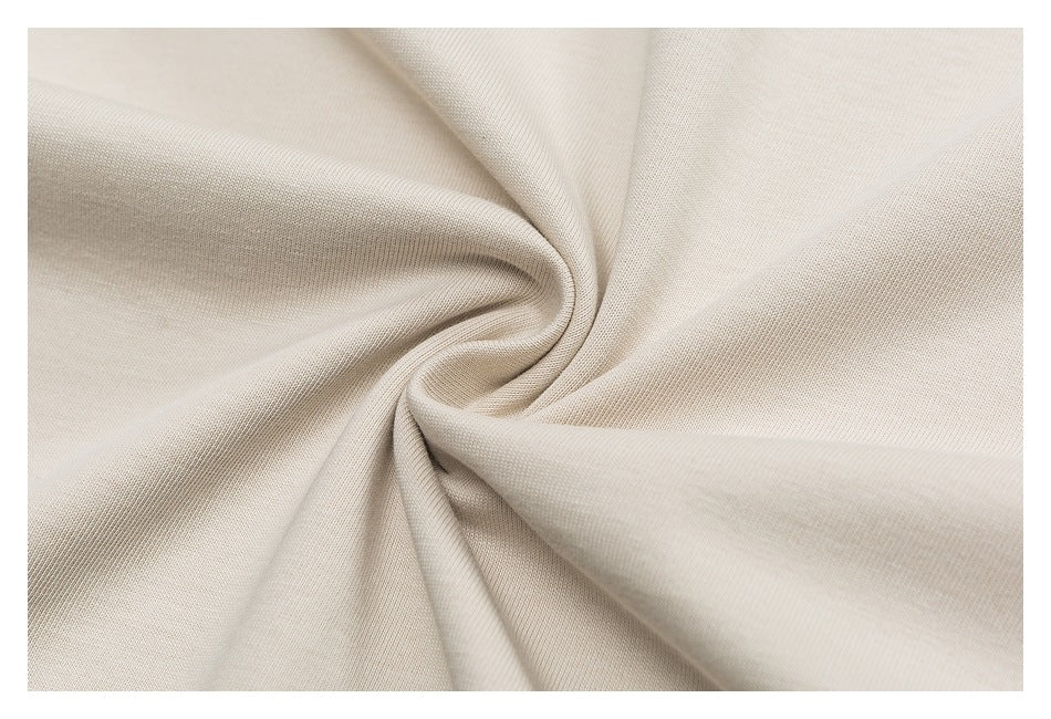 Close-up of cream-colored fabric gathered into soft folds, showing its fine knit texture.
