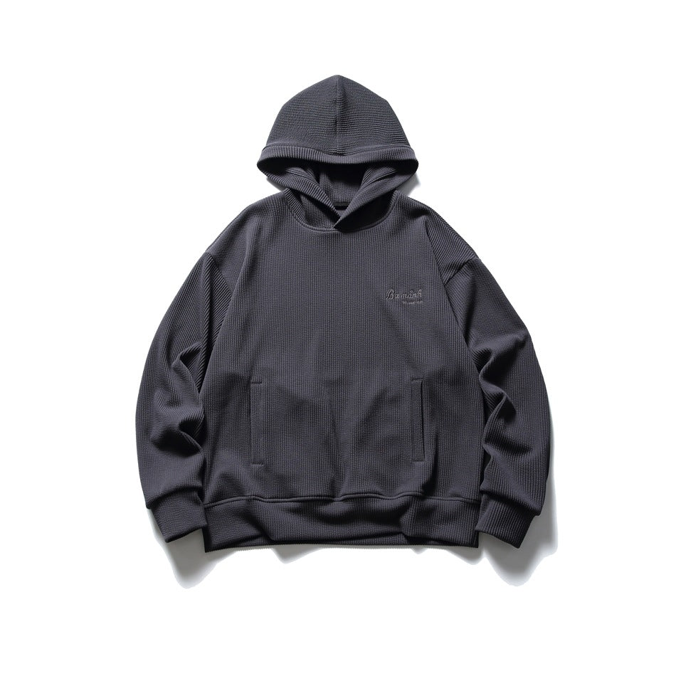 Charcoal gray waffle-knit pullover hoodie flat lay, front view with slit pockets and tonal chest embroidery