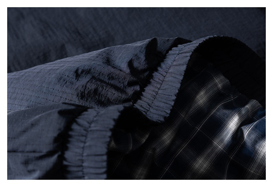Close-up of a dark navy garment with a gathered seam and blue-gray plaid lining.
