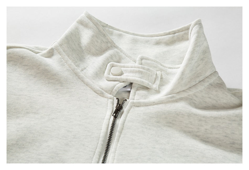 Close-up of a light gray heathered sweatshirt collar with a short metal zipper and snap-tab closure.