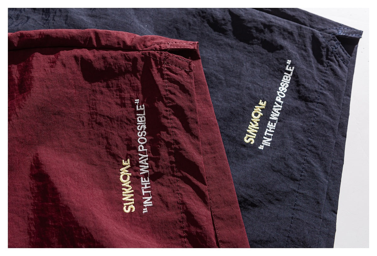Close-up of burgundy and dark navy shorts showing small yellow and white embroidered lettering.