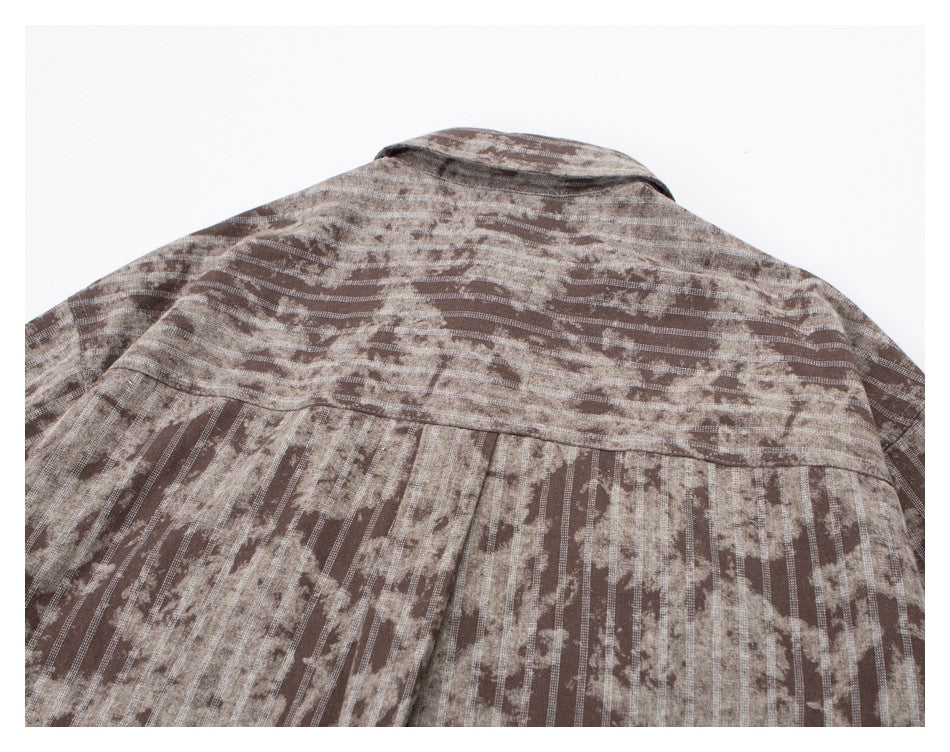 Close-up of the upper back of a brown and beige patterned shirt, including the collar and pleated yoke.