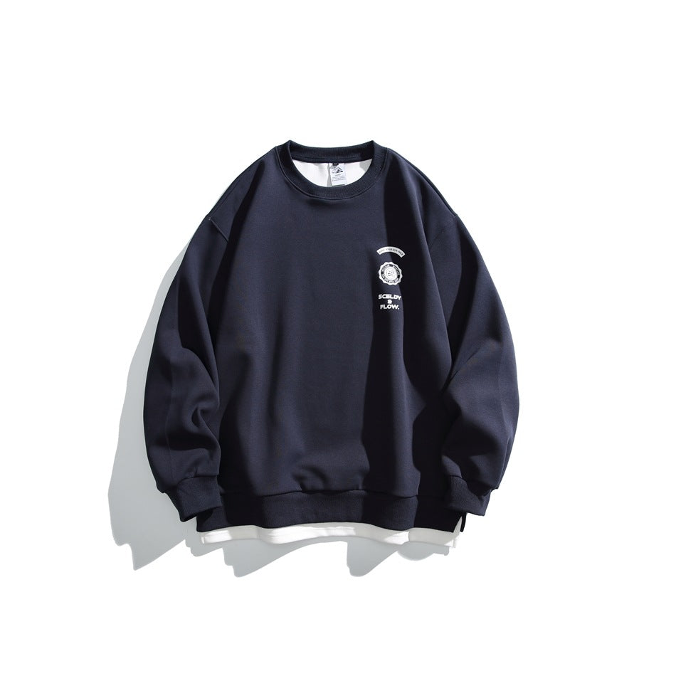 Navy crewneck sweatshirt flat lay with small white chest crest print and white layered underhem