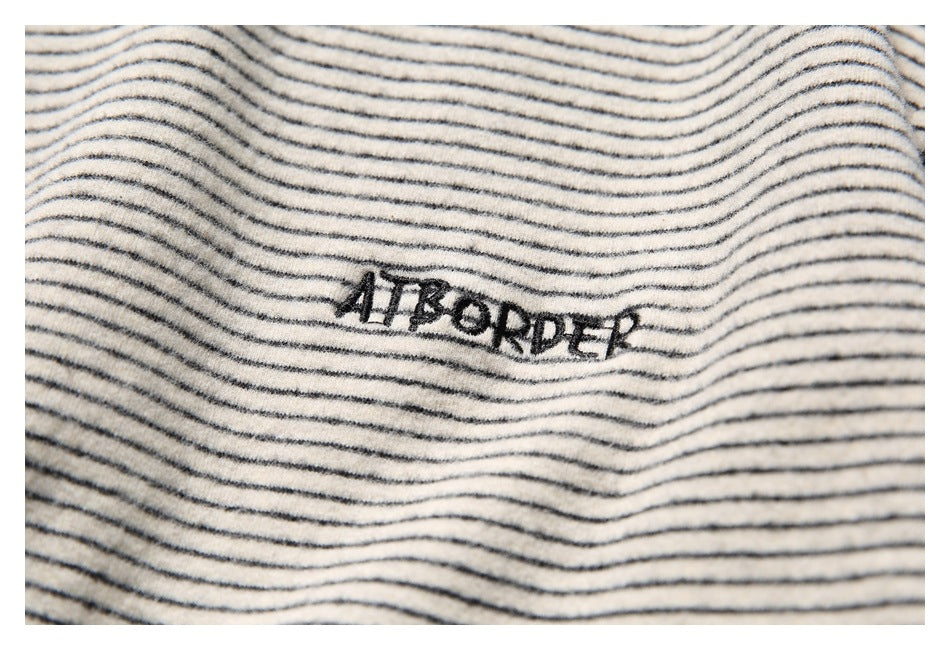 Close-up of black embroidered lettering on cream fabric with thin black stripes.