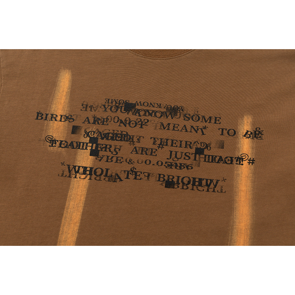 Close-up of black text artwork printed across the chest of a brown T-shirt.