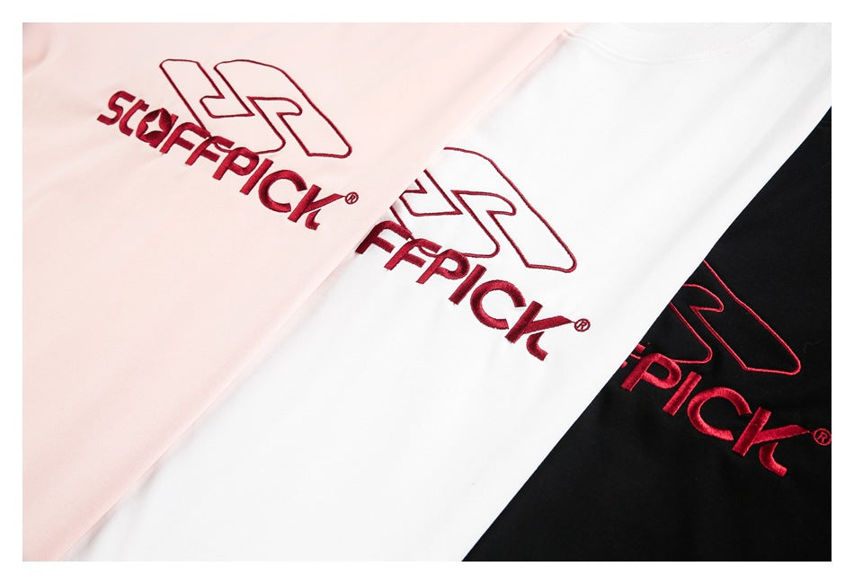 Close-up of burgundy embroidered logos on pale pink, white, and black T-shirts.
