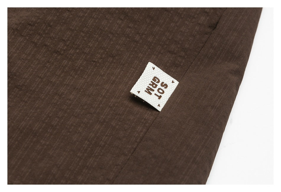Close-up of dark brown fabric with a small white sewn-in label bearing brown lettering.