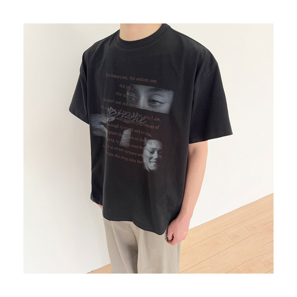 Person wearing the black graphic T-shirt with beige pants, shown from the neck down against a white wall