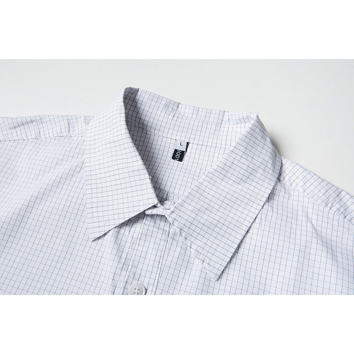 Close-up of a white button-up shirt with a fine gray grid check and pointed collar.