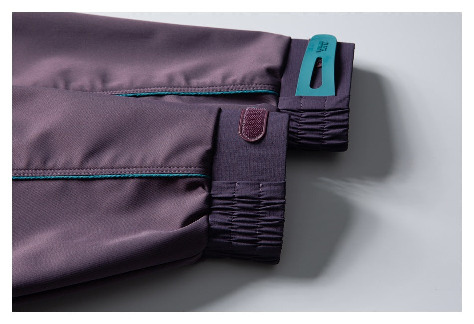 Close-up of purple pant legs with teal piping, gathered cuffs, and a small fastening tab.